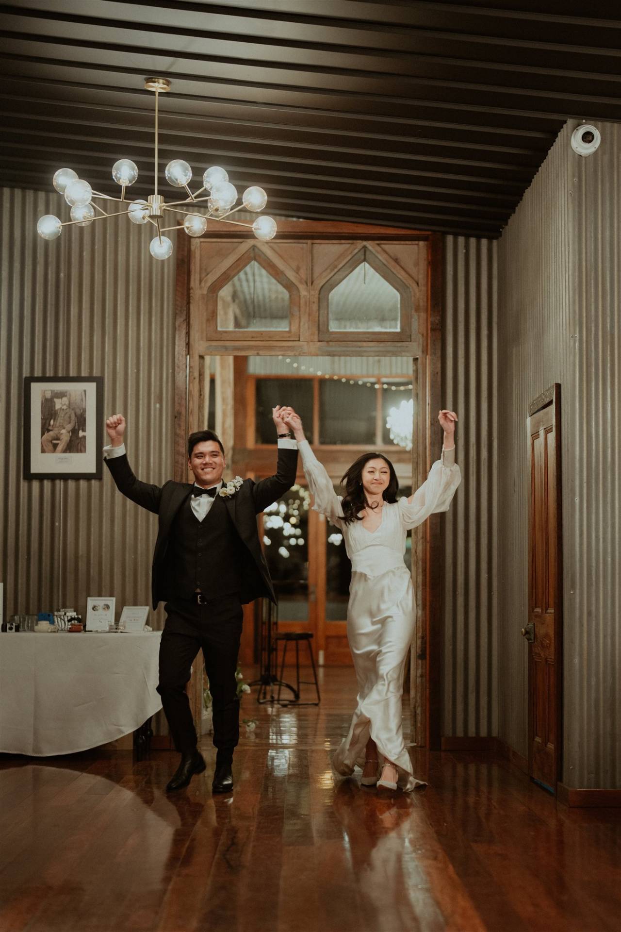 bride and groom holding their hands up