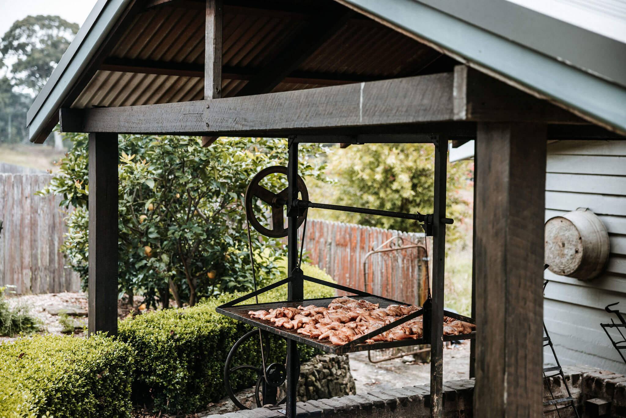 Traditional open barbecue pit with marinated chicken in an outdoor setting, prepping for a rustic wedding feast